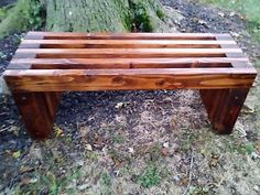 a wooden bench sitting in the grass next to a tree