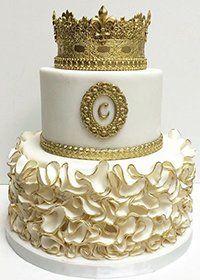 a white and gold wedding cake with a crown on top