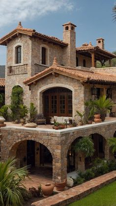 a large stone house with lots of windows and plants in front of the entrance to it