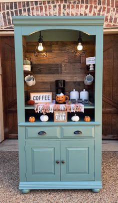 a green cabinet with coffee signs on it and pumpkins in the window behind it