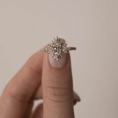 a woman's hand with a diamond ring on top of her finger, showing the center stone