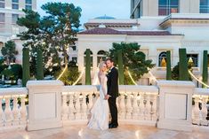 a bride and groom are standing on the balcony at their wedding reception in front of an elegant hotel