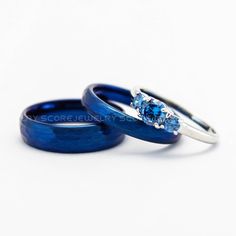 two blue wedding rings with one diamond on top and the other in the middle, against a white background