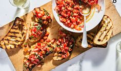 grilled chicken with tomato salsa and garlic bread on a cutting board next to wine glasses