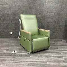 a green recliner chair sitting on top of a hard wood floor next to a wall