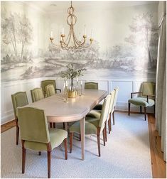 a dining room table with green chairs and a chandelier hanging from the ceiling