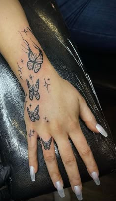 a woman's hand with butterfly tattoos on it