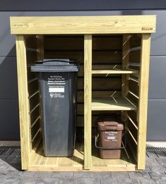 two trash cans are sitting in an open storage area with shelves and bins on the side