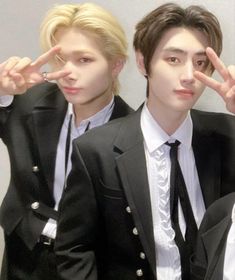 two young men wearing suits and ties posing for the camera with their fingers in the air