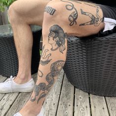 a man with tattoos on his legs sitting next to a wicker chair and potted plant