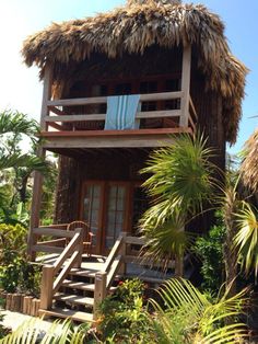 a small house with a thatched roof and stairs leading to the upper level deck