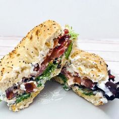 a sandwich cut in half sitting on top of a white plate with lettuce and bacon