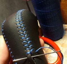 a person is stitching the stitches on a baseball ornament with blue thread