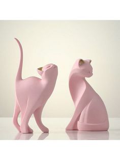 two pink cat figurines sitting next to each other