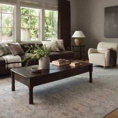 a living room with couches, chairs and a coffee table in front of a window