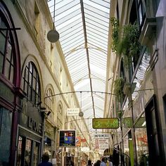 people are walking down an alley way in a shopping district with high ceilings and arched windows