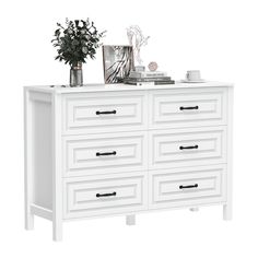 a white dresser with drawers and vases on top