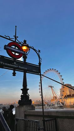 a street sign with the london eye in the background