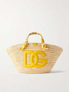 Dolce & Gabbana's 'Kendra' tote celebrates the "ancient ceramics of Caltagirone". It's woven from raffia and detailed with a large leather logo, plus silk-twill wrapped like a scarf around the handles. The joyful design makes it the perfect choice for summer and you'll have plenty of space for your essentials - think phone, wallet and your current book. Designer Natural Straw Bag With Handles, Designer Natural Straw Bag, Designer Straw Bags With Intrecciato Weave, Designer Straw Bag With Intrecciato Weave For Vacation, Designer Straw Top Handle Bag, Luxury Summer Straw Bag With Intrecciato Weave, Designer Summer Bags With Intrecciato Weave, Designer Natural Straw Bag With Gold-tone Hardware, Designer Bags With Intrecciato Weave For Summer