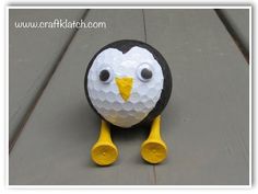 a golf ball shaped like a penguin with yellow feet and beaks on the ground