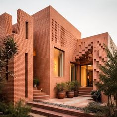 a large brick building with steps leading up to it and potted plants on the side