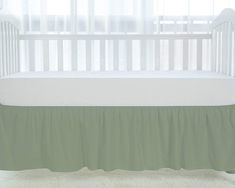 a white crib with a green bed skirt