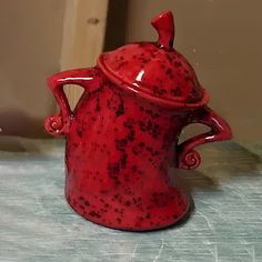 a red ceramic tea pot sitting on top of a table