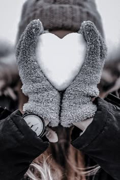 a person holding up a heart shaped snowball in front of their face with both hands