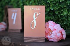 the table numbers are placed next to pink flowers