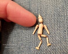 a tiny wooden figure is placed on the lap of someone's blue jean jacket