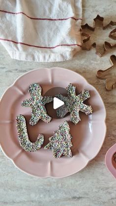 some cookies are on a pink plate with sprinkles next to one another