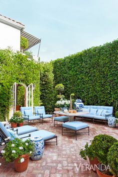 a blue and white couch sitting on top of a patio next to potted plants