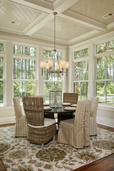 an image of a dining room setting with chairs and a rug on the floor in front of large windows