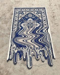 a blue and white rug on the ground with an artistic design in it's center