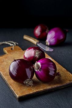 three red onions on a cutting board with a knife and fork next to it, in arabic