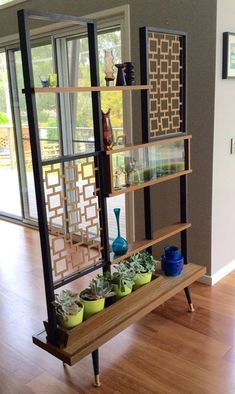 a shelf with plants and vases on top of it in front of a sliding glass door