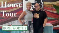 a man and woman standing next to each other in front of a wall with the words house tour on it