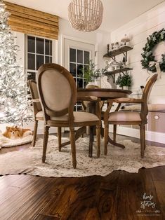 a dining room table with chairs and a christmas tree in the background