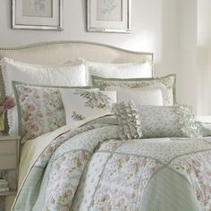 a bed with floral comforter and pillows on top of it in front of two framed pictures