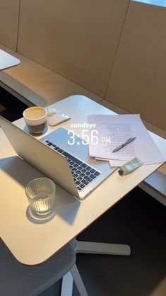 an open laptop computer sitting on top of a wooden table next to a cup and saucer