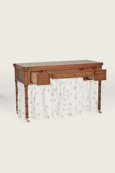 a wooden table with two drawers and a curtain on the bottom shelf, against a white background