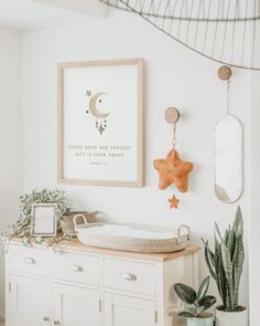 a baby's room with a crib, potted plant and pictures on the wall