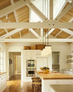 an open kitchen with white cabinets and wood flooring is pictured in this image, there are two stools on the counter