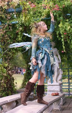 a woman dressed up like a fairy standing on some steps in front of a tree