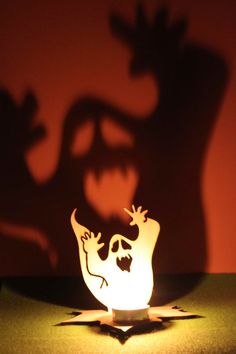 the shadow of a person's head on a table next to a lit candle