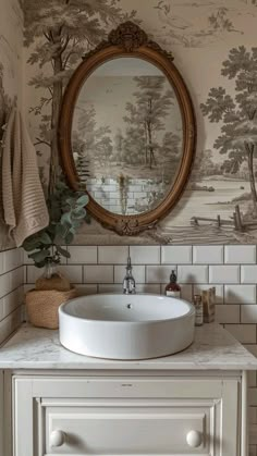 a white sink sitting under a mirror in a bathroom next to a wallpapered wall