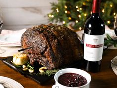 a large roast sitting on top of a table next to a bottle of wine