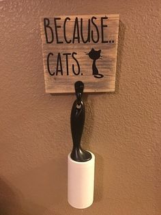 a toilet paper dispenser with a sign on it that says because cats