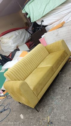 a yellow couch sitting on top of a dirty floor