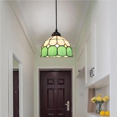 a light hanging over a kitchen counter next to a door with flowers on the floor